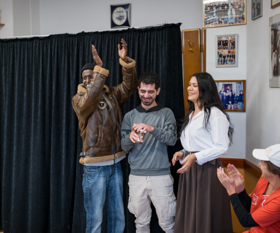 Drei Personen performen vor einem schwarzen Vorhang.